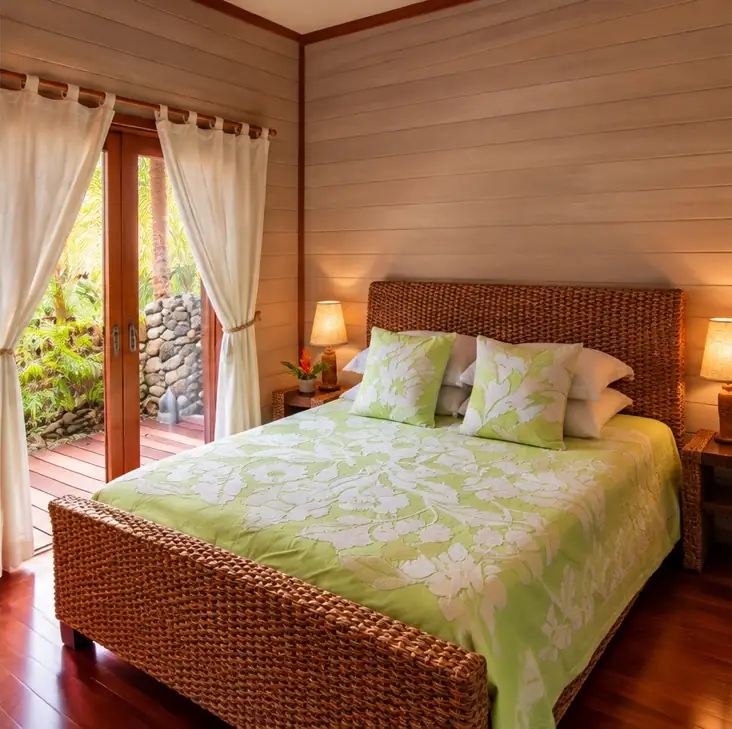 Chambre avec lit queen size en rotin et dessus-de-lit vert à motifs tropicaux