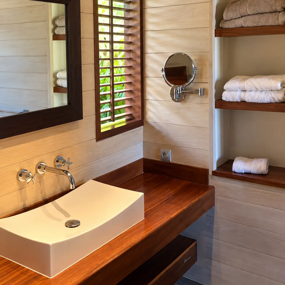 Salle de bain en bois avec vasque blanche et persiennes